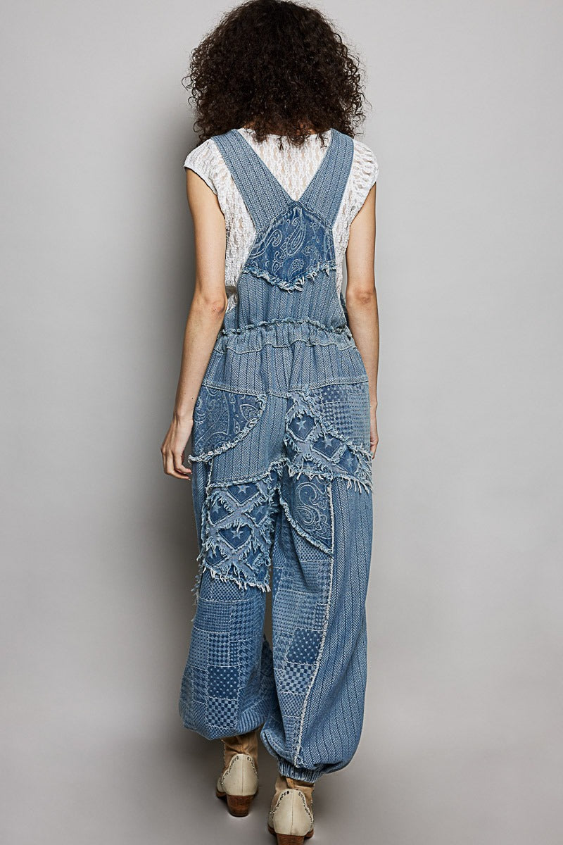 Person wearing a denim overalls with lace details on a plain background