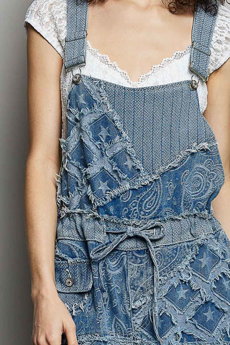 Person wearing a blue denim dress with ruffled details on a plain background