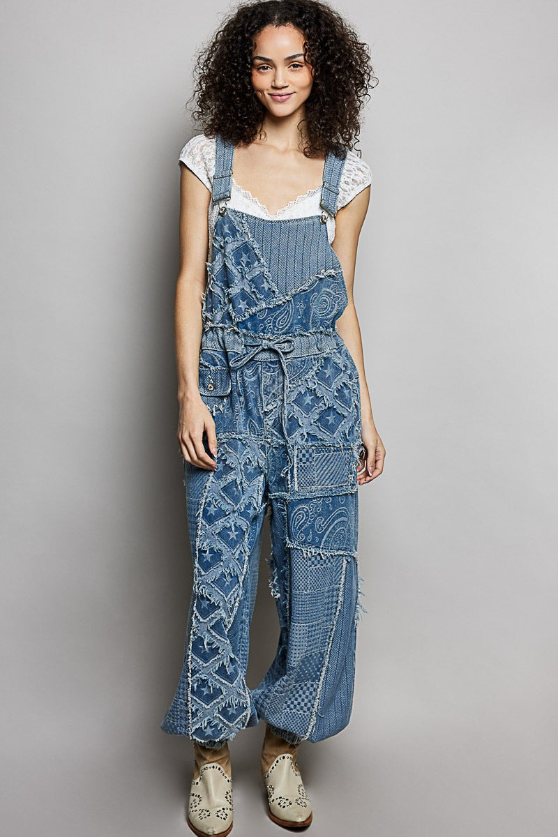 Woman wearing blue patterned denim overalls against a gray background