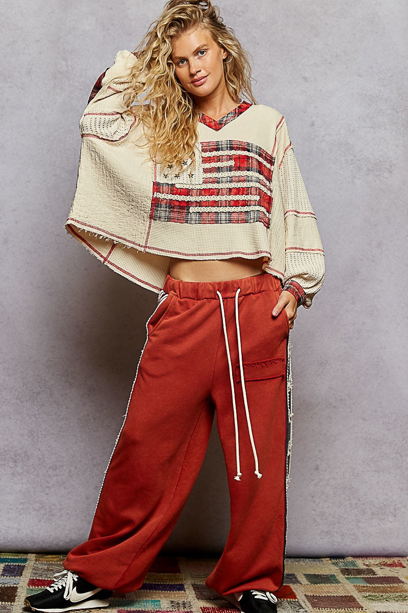 Woman wearing a plaid top and red pants against a gray background
