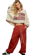 Woman wearing a patterned top and red pants on a white background