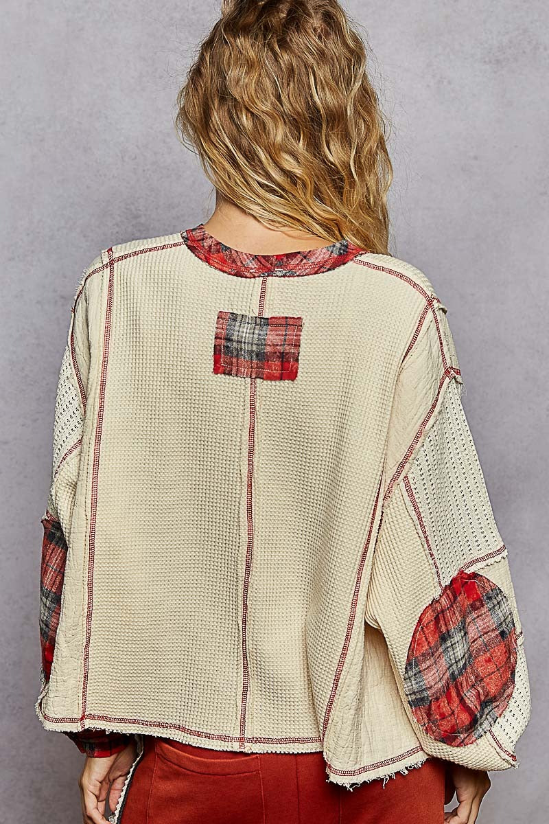 Person wearing a patchwork-style top with plaid patterns on a gray background