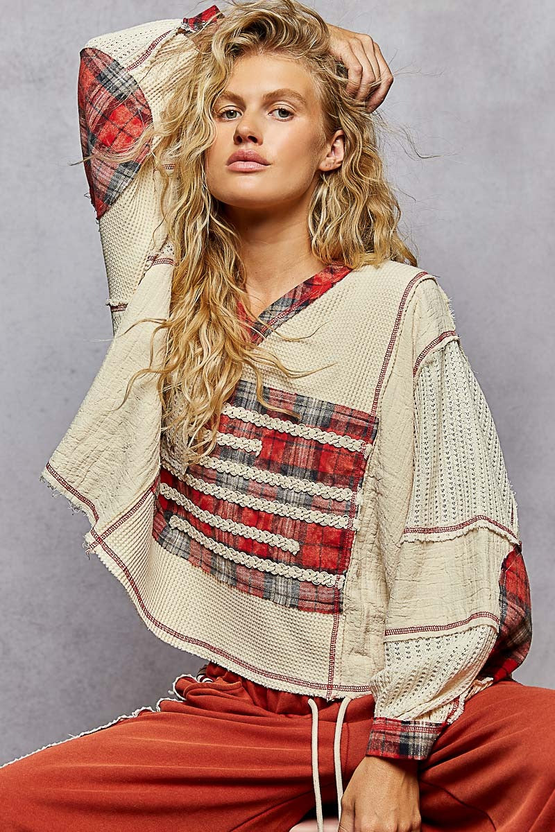 Woman wearing a plaid top and beige cardigan against a gray background