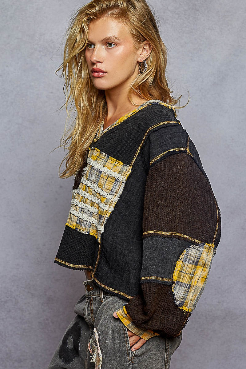 Woman wearing a black and yellow patterned sweater against a gray background