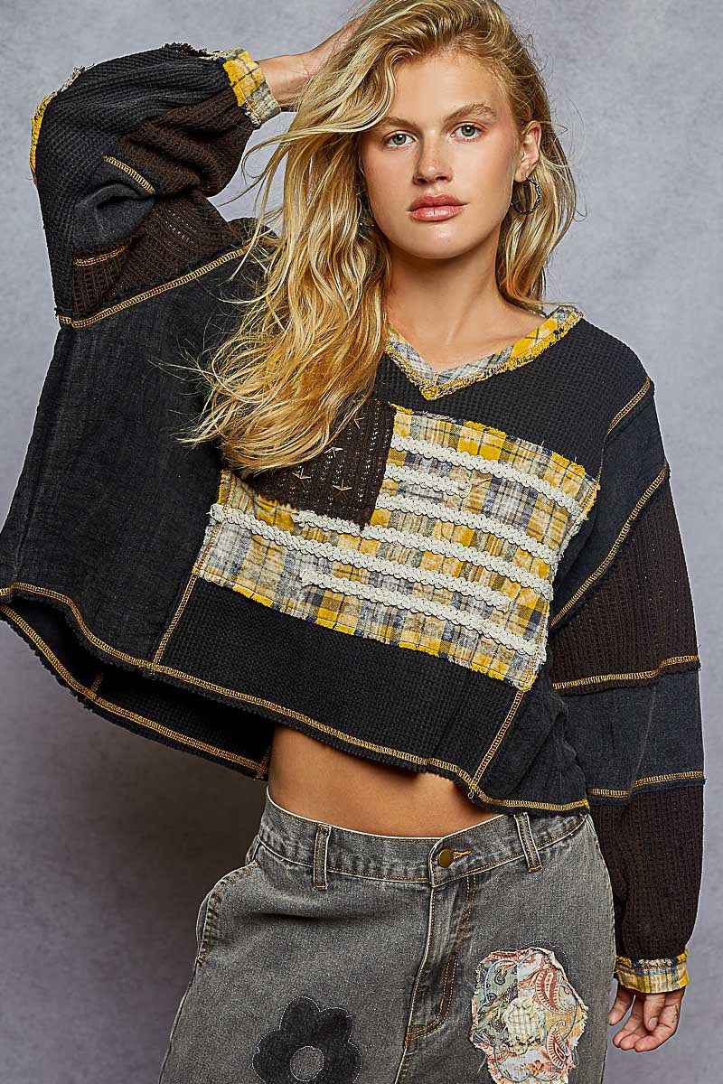 Woman wearing a black and yellow patterned sweater with a gray background