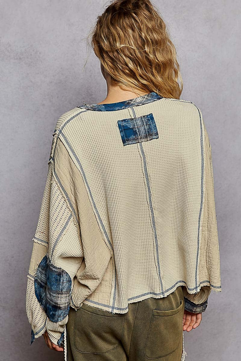 Person wearing a beige and blue patterned shirt with a gray background