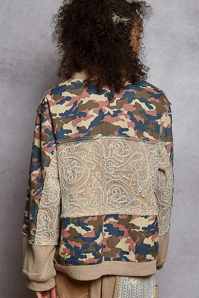 Person wearing a camouflage and paisley patterned jacket against a gray background