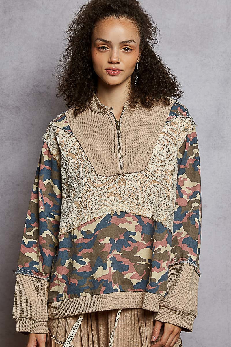 Person wearing a patterned jacket with camouflage and lace design on a gray background