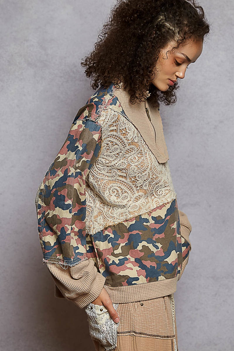 Person wearing a camouflage jacket with paisley patterns against a gray background