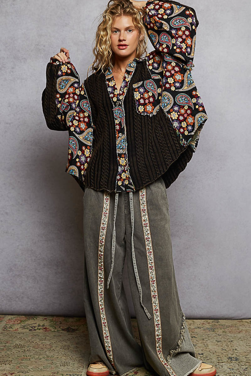 Person wearing a floral embroidered jacket and gray pants against a plain background