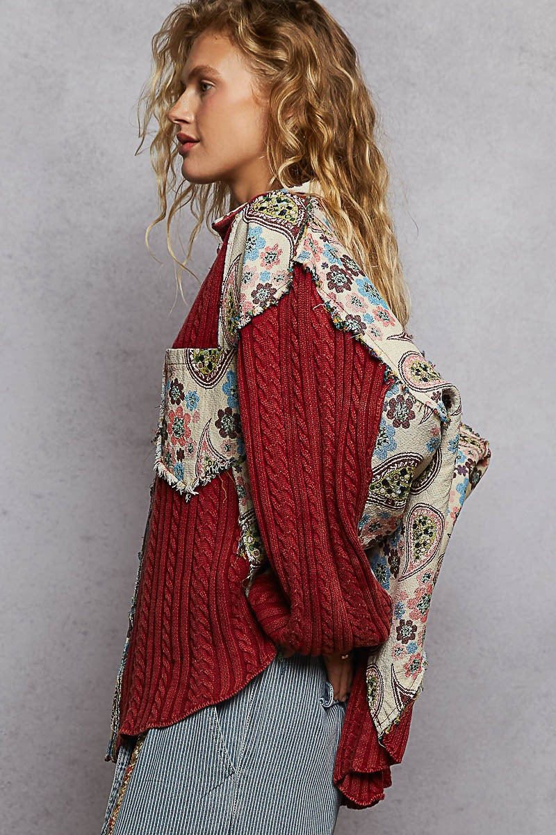 Woman wearing a red knitted sweater with a floral pattern over it against a gray background