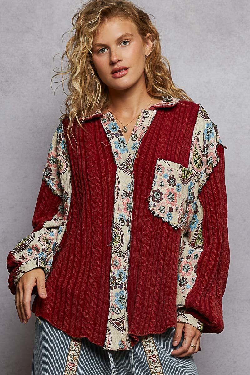 Woman wearing a red cable knit cardigan over a patterned shirt with a gray background