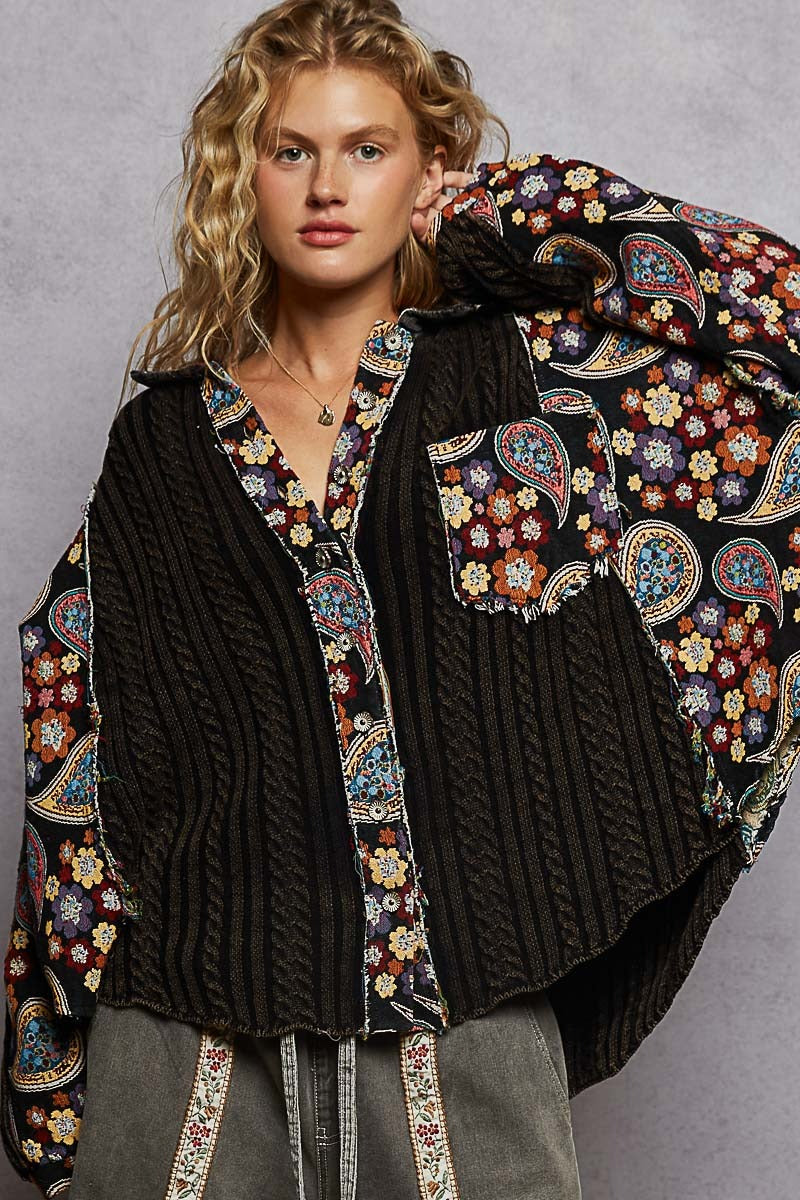 Woman wearing a black jacket with colorful paisley patterns on a gray background