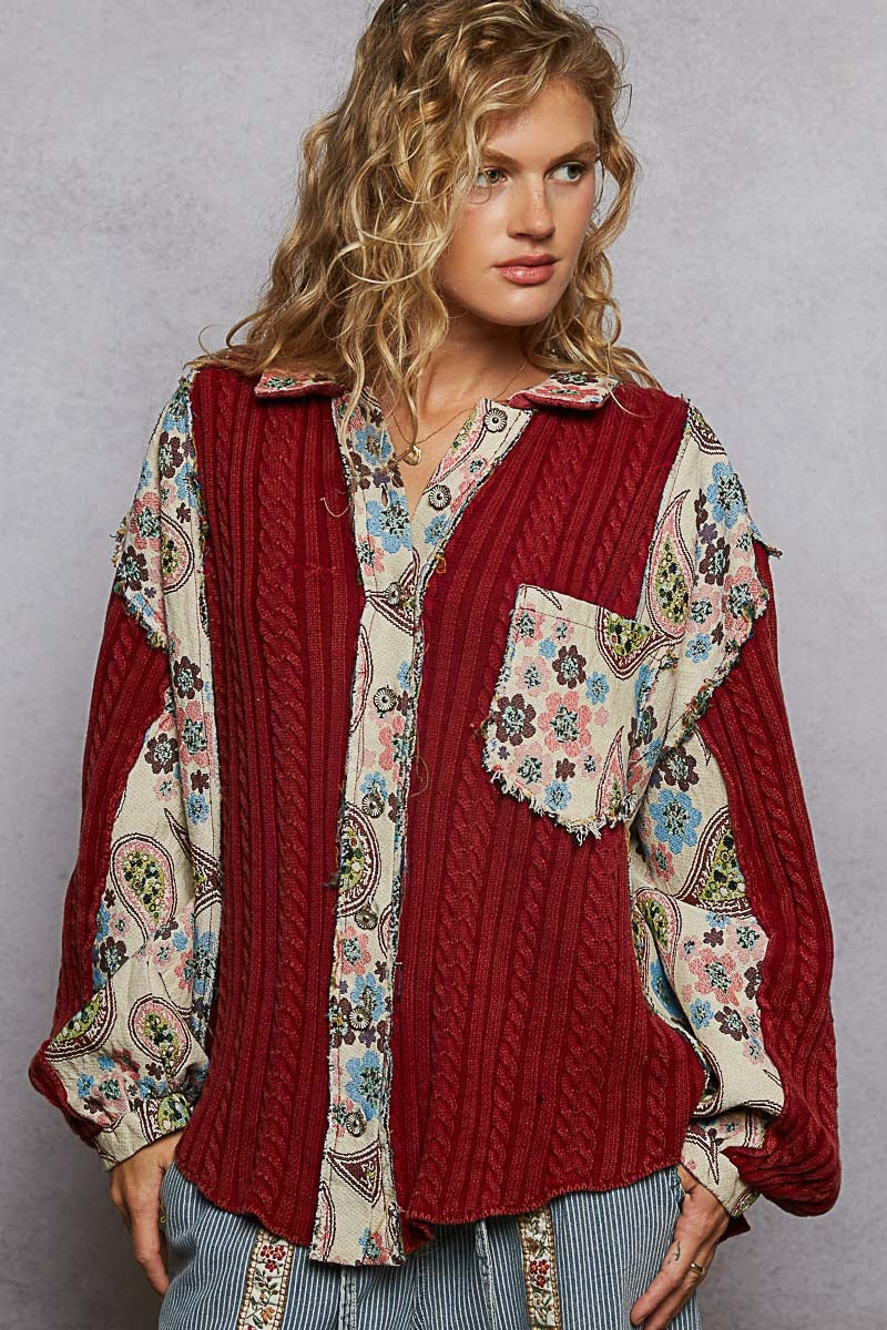 Woman wearing a red cable knit sweater with floral patterns on a plain background