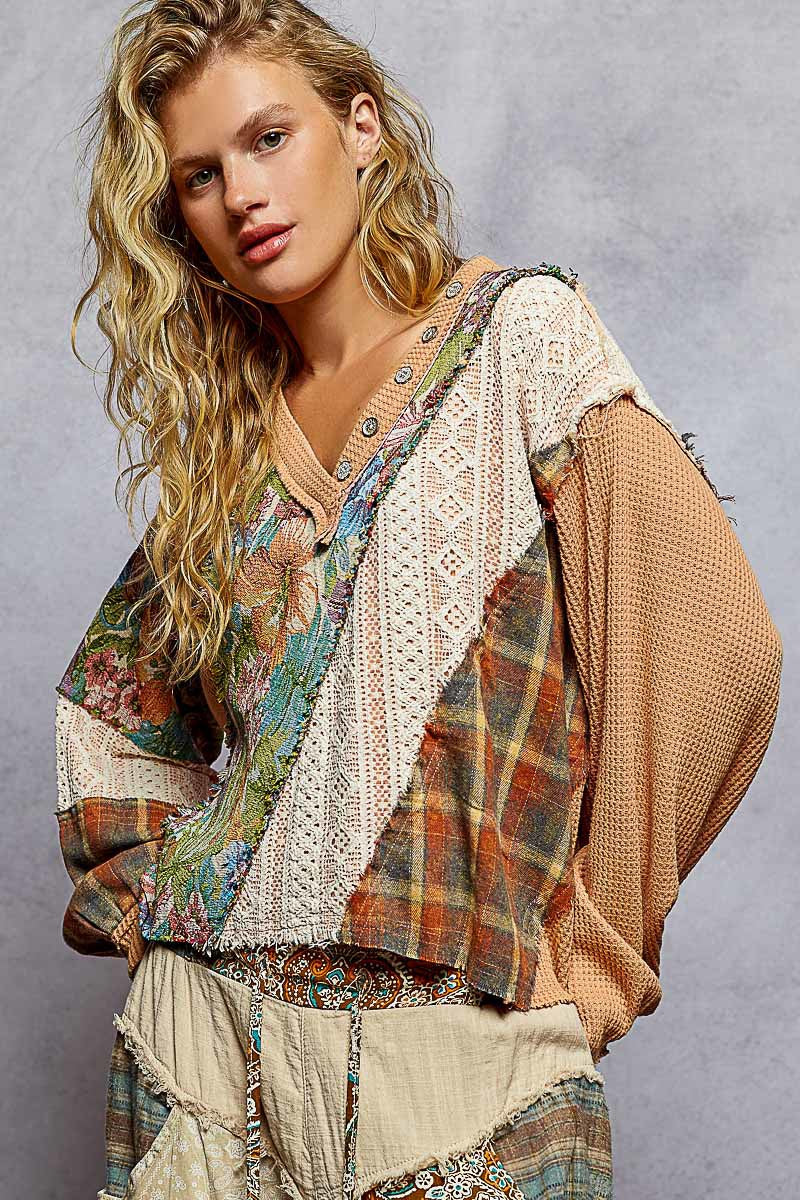 Woman wearing a bohemian-style outfit with a patterned jacket and beige top against a gray background