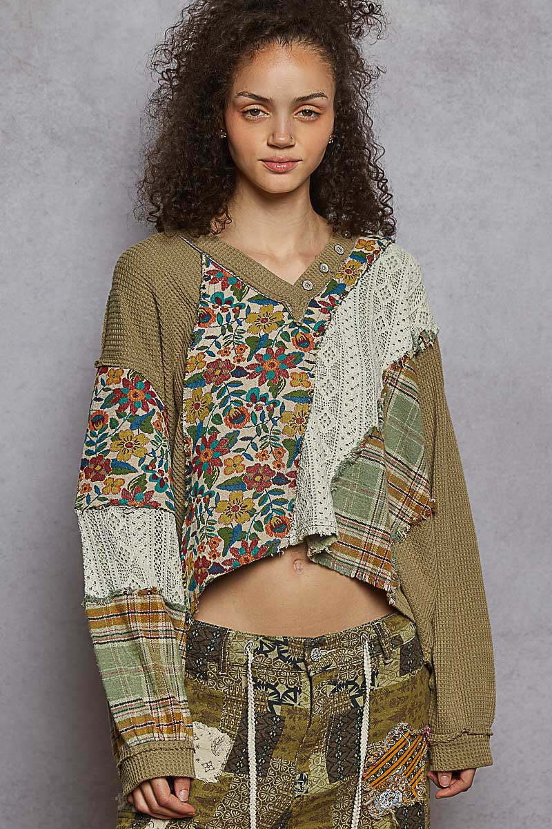 Woman wearing a patchwork outfit with a floral top and patterned pants against a gray background