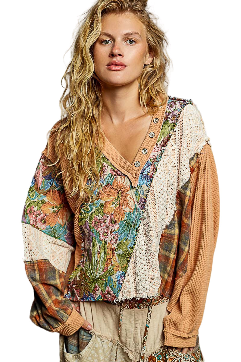 Woman wearing a colorful floral and plaid patterned top with a white lace overlay on a white background