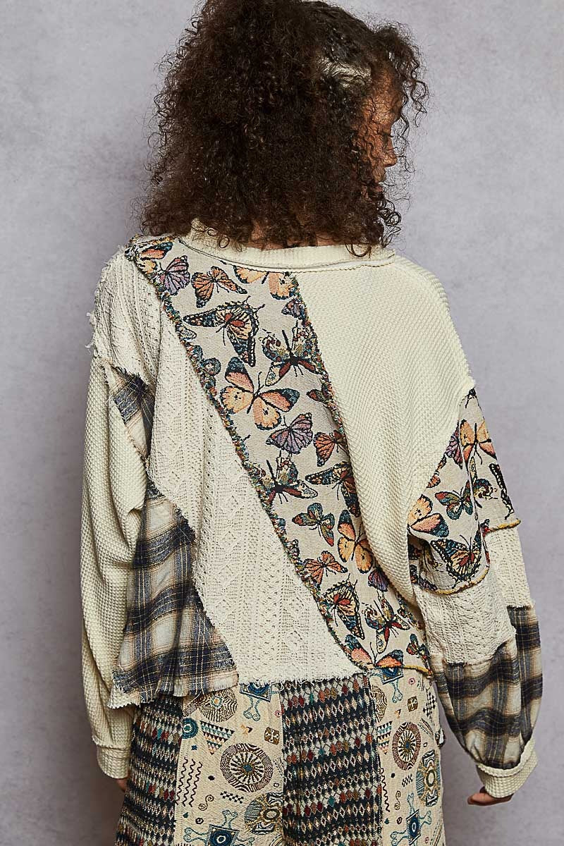 Person wearing a patterned cardigan with butterfly designs on a plain background