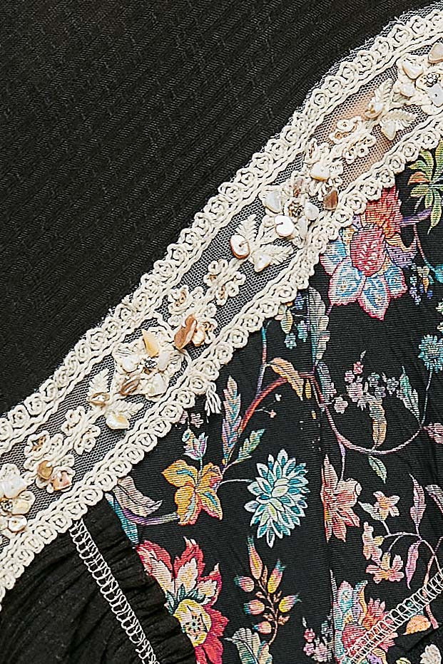 Close-up of floral embroidery on a black fabric with lace trim