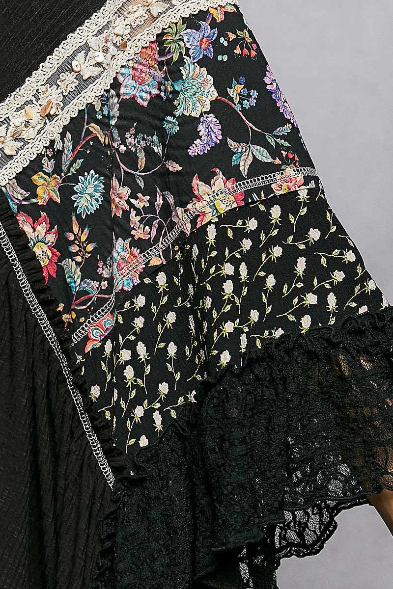 Black floral embroidered fabric with lace trim on a gray background