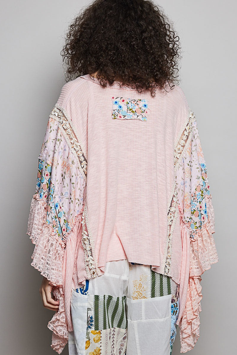 Person wearing a pink kimono with floral embroidery on a plain background