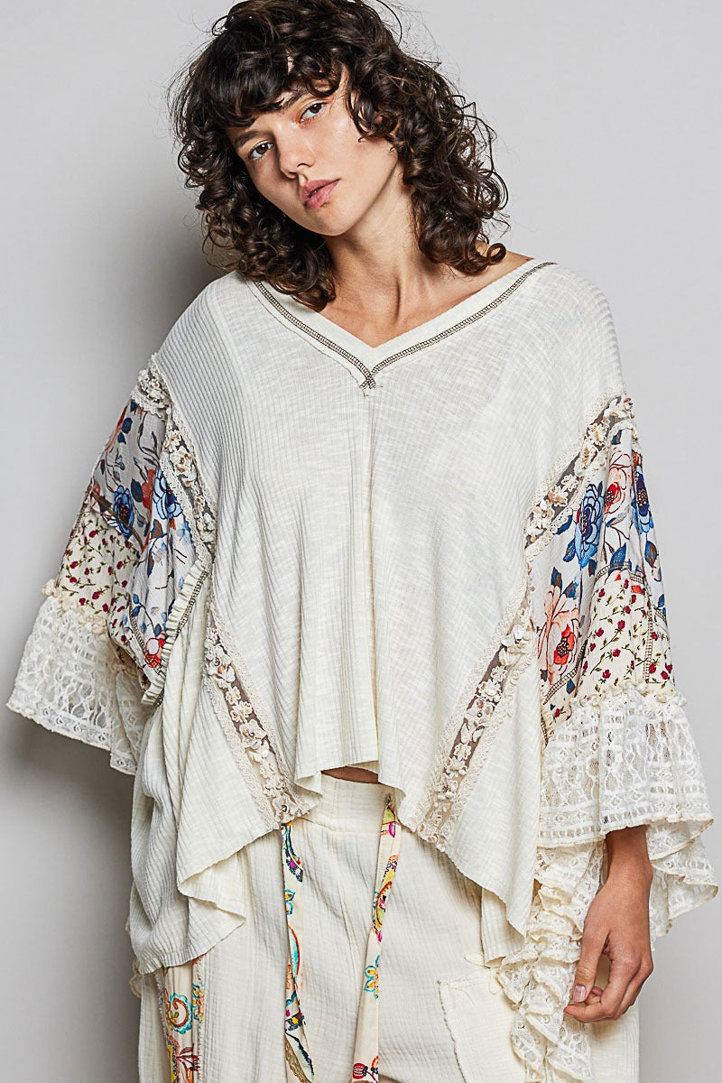 Woman wearing a white outfit with floral sleeves against a plain background