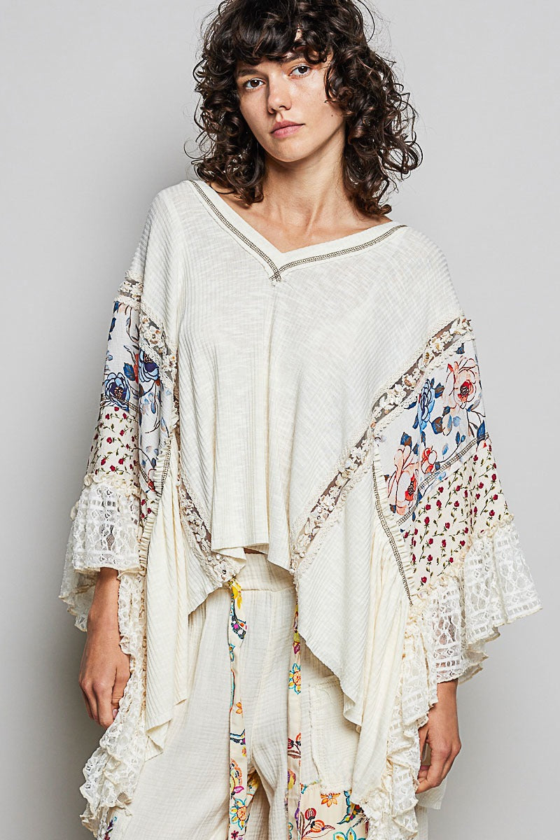 Woman wearing a cream-colored outfit with floral embroidery on a plain background