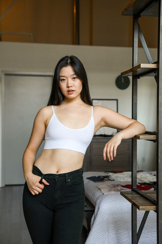 a woman standing next to a bed in a room
