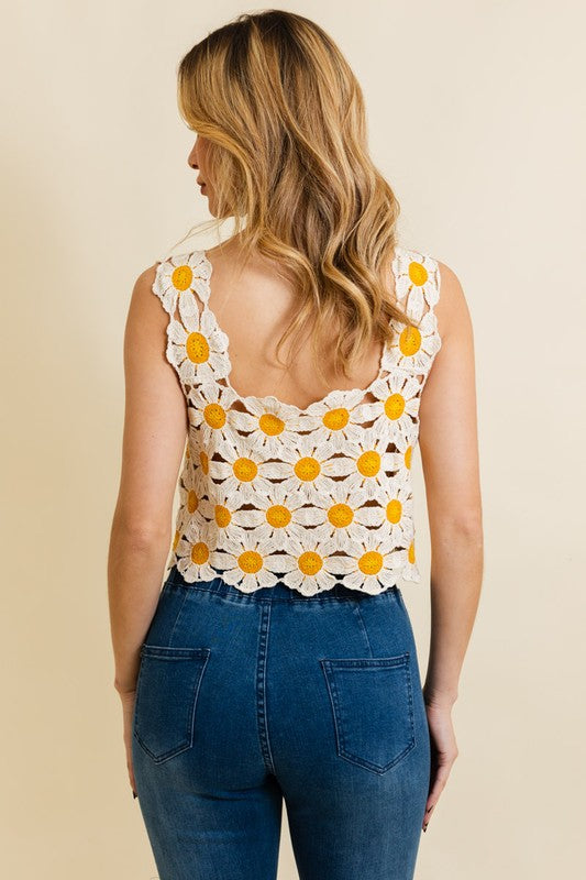 a woman wearing a white crochet top with yellow flowers