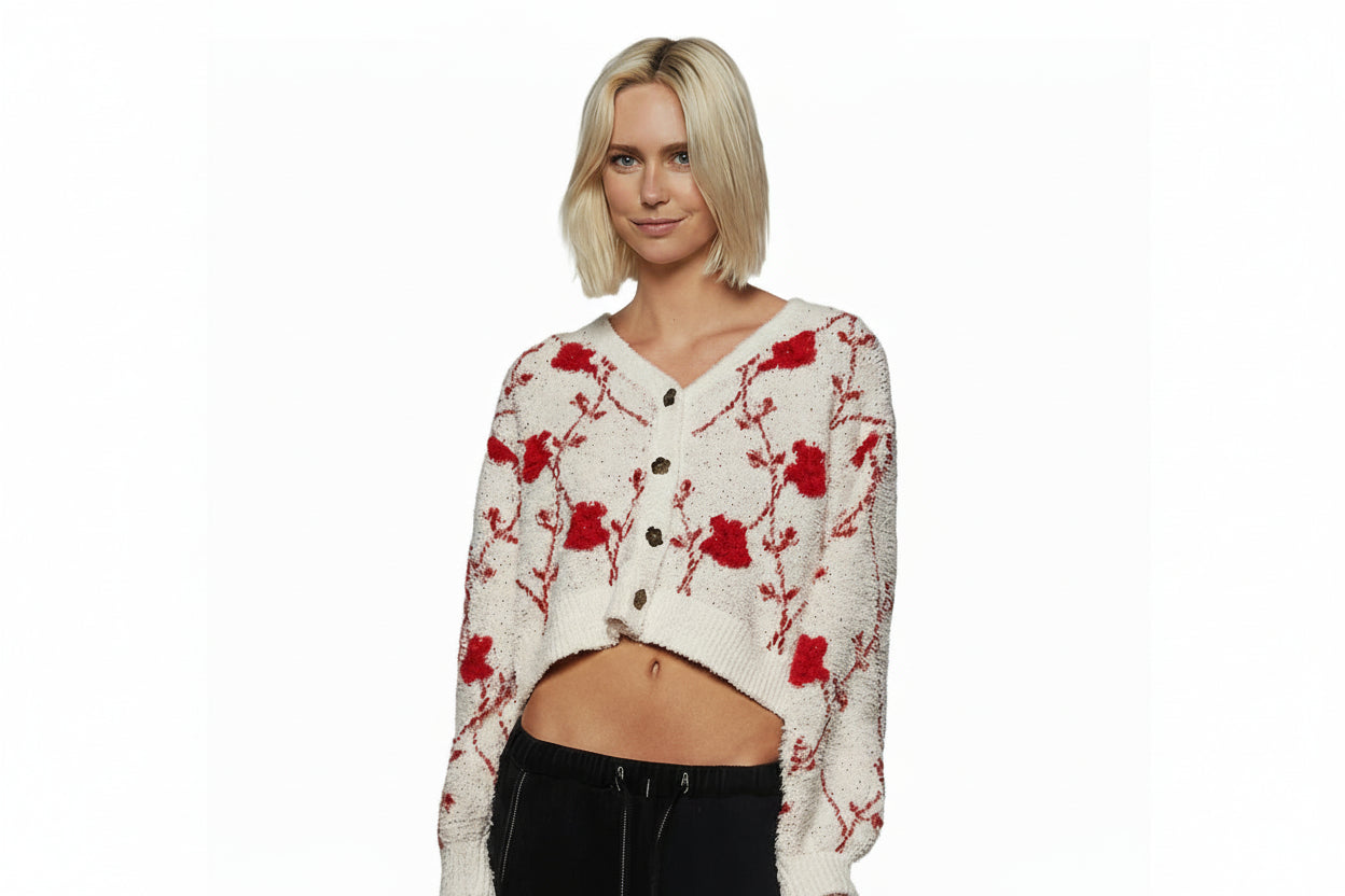 Woman wearing a white cardigan with red floral patterns against a gray background