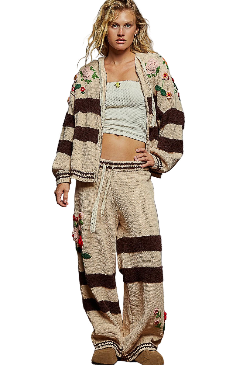 Woman wearing a floral cardigan, top, and wide-leg pants against a plain background