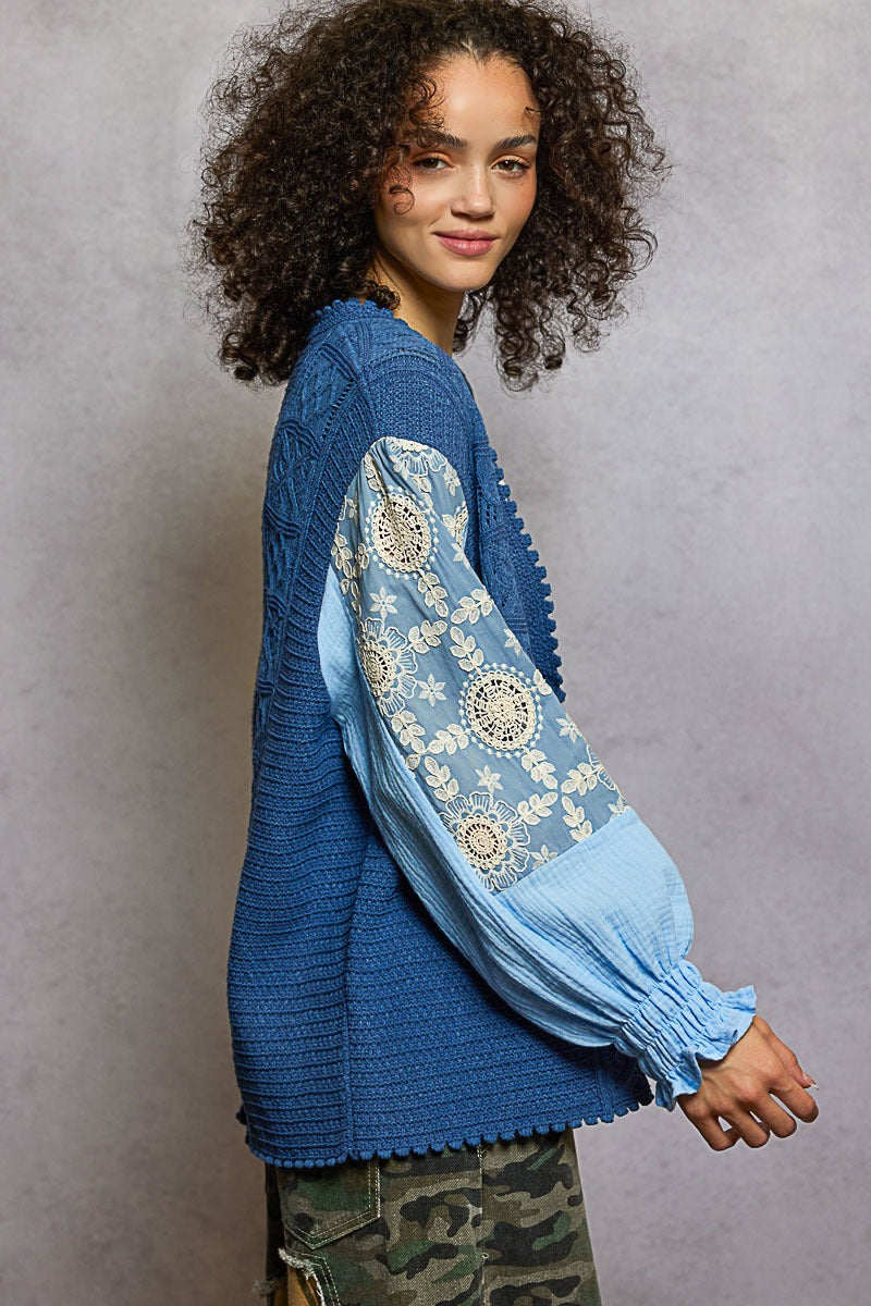 Woman wearing a blue sweater with floral patterns on a gray background
