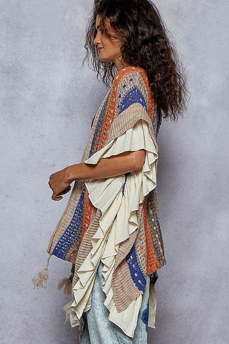 Woman wearing a colorful, patterned shawl against a gray background