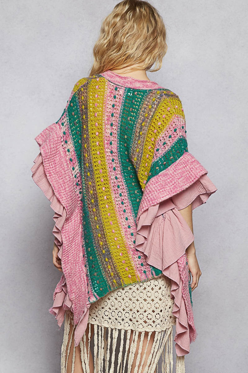 Woman wearing a colorful, patterned shawl with ruffled edges on a plain background