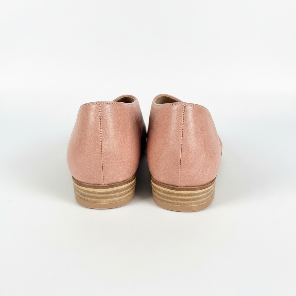Pair of pink leather shoes with brown soles on a white background