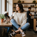 Woman seated in a café reading a book and holding a coffee cup, wearing camouflage canvas sneakers
