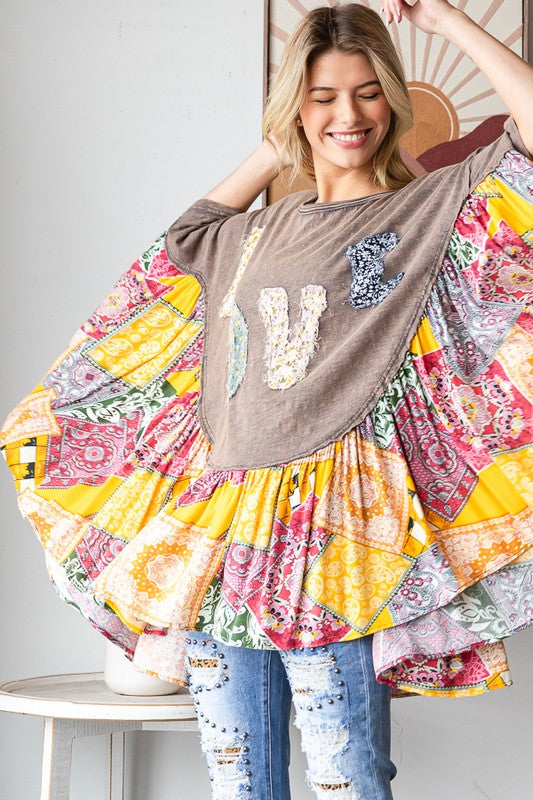 Woman wearing a colorful patchwork dress with a brown top and ripped jeans indoors.