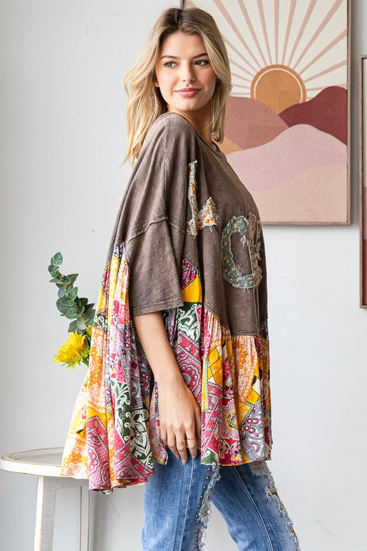 Woman wearing a colorful patterned dress over a brown cardigan in a room with abstract art on the wall.
