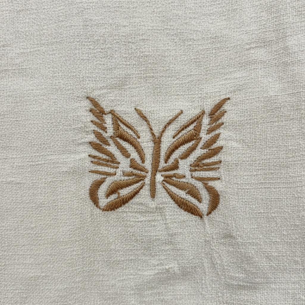 Close-up of ivory woven fabric texture and gold butterfly embroidery detail on women's wide-leg pants