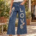 POL Clothing indigo pants with lace LOVE appliqué and flower detail in a courtyard