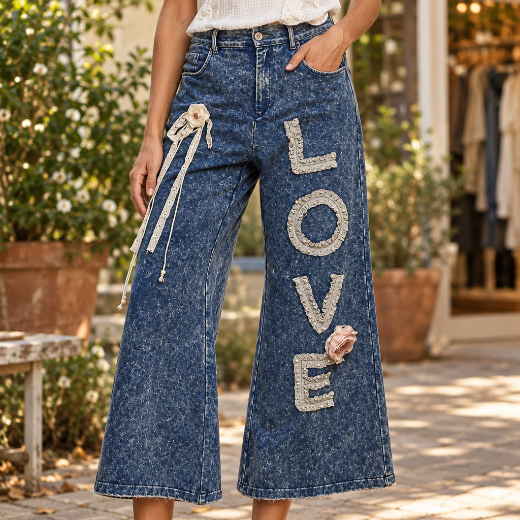 POL Clothing indigo pants with lace LOVE appliqué and flower detail in a courtyard