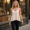 Cream scalloped knit camisole layered over white with dark jeans, walking past a bookshop