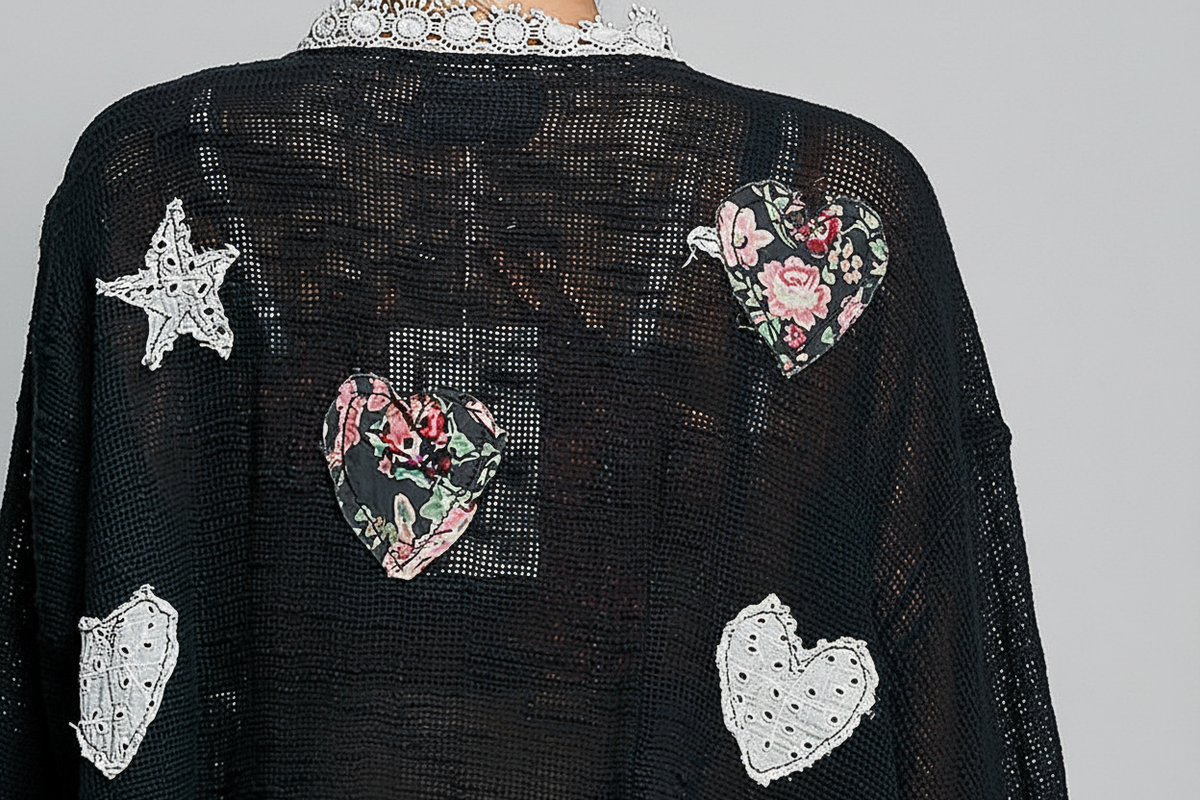 POL Clothing black open-knit cardigan close-up showing mixed floral heart and star appliqué patches with white crochet lace trim