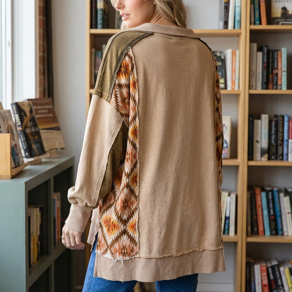 Back detail of a tan pullover with olive shoulders, geometric side panels and a longer hem in a bookshop