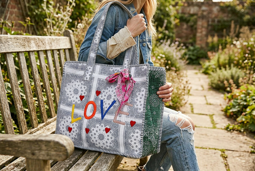 Woman carrying a paisley tote on her shoulder beside a garden bench
