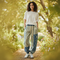 Woman wearing blue patchwork joggers with colorful butterfly print and elastic waist styled casually lifestyle photo with bokeh background
