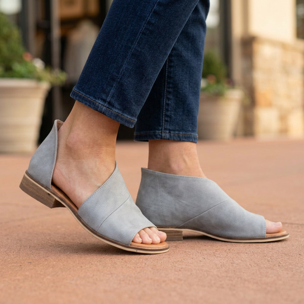 Close-up of women's gray bootie sandals showing cutout and covered sides with dark cropped jeans