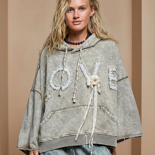 Close-up of POL Clothing LOVE crochet lace applique hoodie in taupe wash, cream floral pin and braided drawstring