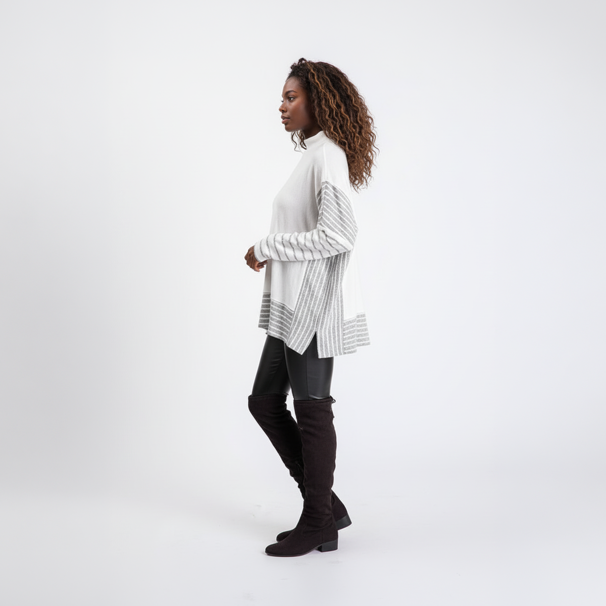 Women's white striped knit pullover sweater side profile studio white background black leather pants chic