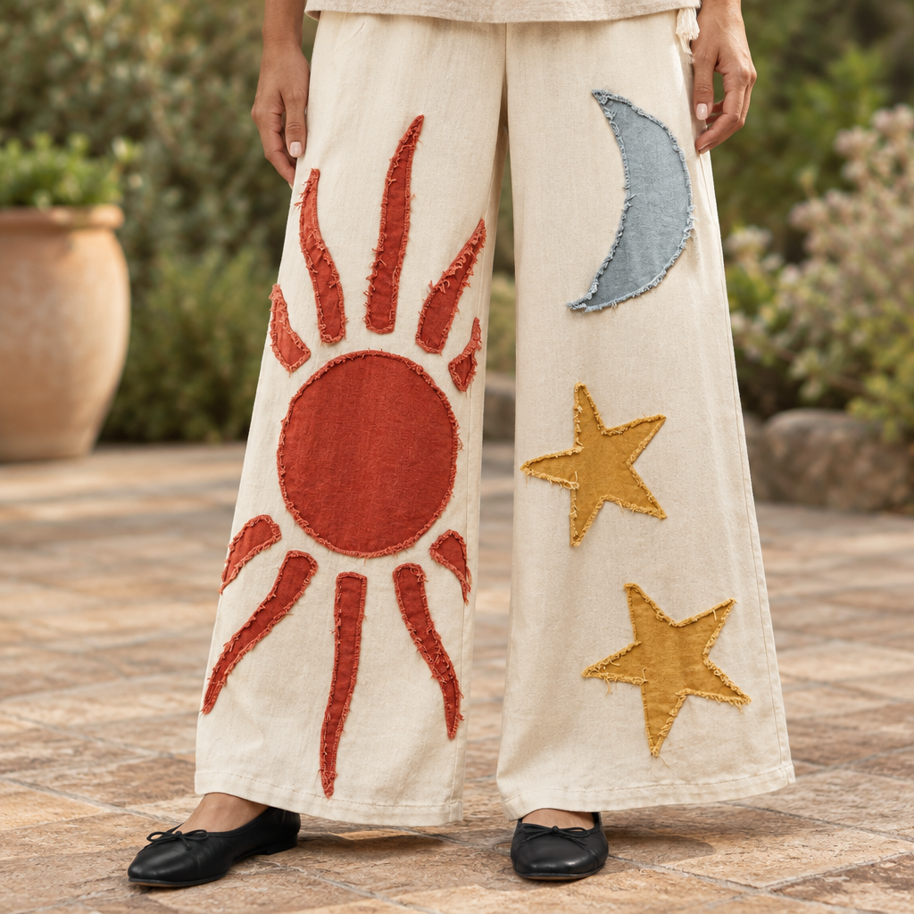 Mello women's cream wide-leg pants detail showing rust sun, blue-gray moon and mustard star appliqués